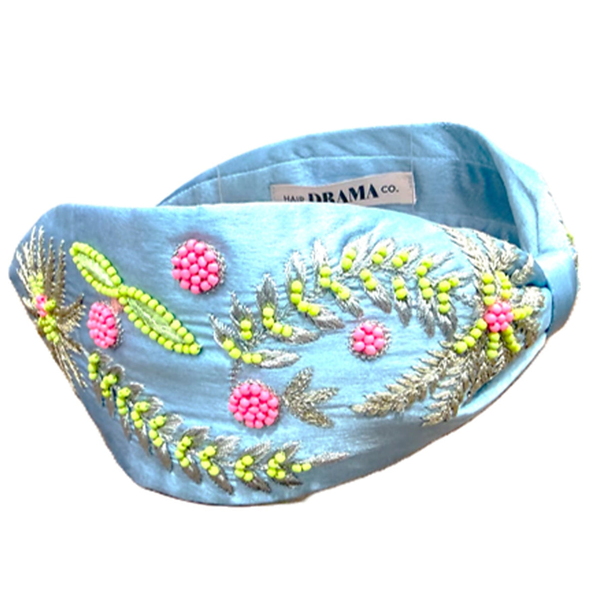 A light blue fabric headband with intricate beadwork and embroidery featuring pink flowers, green leaves, and silver accents, displayed on a clean white background.
